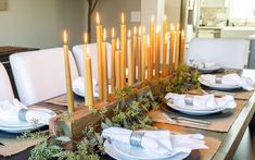 a dining room table set with candles and place settings