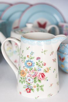 a close up of a pitcher on a table with other dishes in the back ground