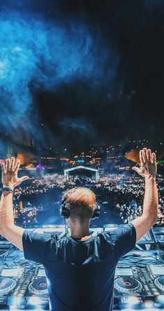 a man with headphones on standing in front of a cityscape at night