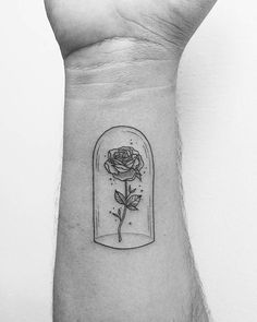 a rose in a glass jar tattoo on the left inner arm and wrist, it is black and white