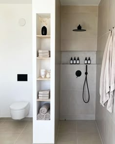 a white bathroom with black and white accessories on the shelf next to the shower head