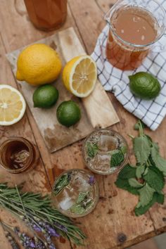 three glasses of tea, lemons and herbs on a wooden table