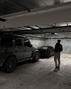 a man standing next to two cars in a parking garage