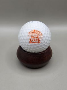 a white golf ball sitting on top of a wooden stand with an orange and white logo