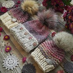 two knitted hats sitting on top of a wooden table next to flowers and doily