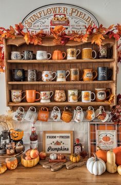 a wooden shelf filled with coffee mugs and other fall items on top of a table