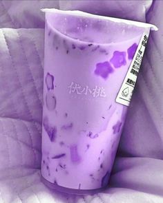 a purple cup with some writing on the top and bottom is sitting on a bed