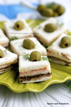 small sandwiches with olives are on a green plate