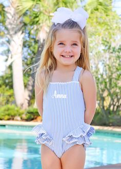 Prepare for delightful summer fun with our Santorini Blue One Piece Swimsuit. Offering UPF 50 sun protection, the blue stripe swimsuit features cross straps and ruffle trim adorned with white ric-rac trim. Make it uniquely yours by adding a monogram for a personalized touch!Childrens swimsuits, summer vacation, summer 2024, little girls swimsuit, little boys swimsuit, one piece, two piece, little girls bikini, rash guard, boys swim trunks, New swimwear, santorini, european summer, greece, Classic Whimsy Swim, Dallas, Texas, Spring Break, Summer 2024, Beach, Travel, Swim, Pool, Swim Lessons, Kids Swim, Island, tropical vacation, sand, towels, cute swimsuits, girly swimsuits, stripe swimsuits, pink, blue