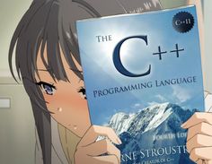 a girl holding up a book with the c + + programming language written on it