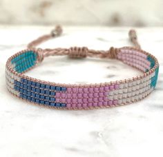 a pink, blue and white beaded bracelet on a marble counter top with a knot