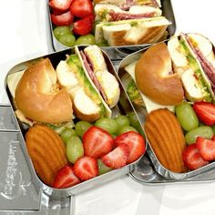 four tins filled with sandwiches and fruit