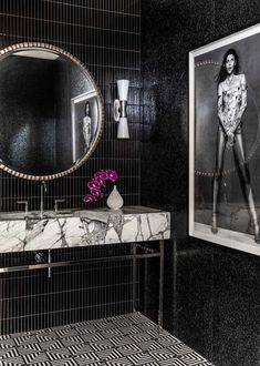 a black and white bathroom with a marble sink, mirror and art on the wall