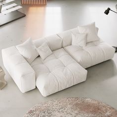 a large white couch sitting on top of a floor next to a table and lamp