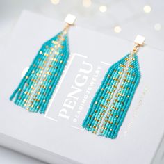 a pair of blue beaded earrings sitting on top of a white box