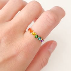 a woman's hand with a rainbow colored ring on top of her finger,