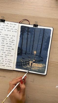 a person is writing on a notebook with a light in the middle and trees behind them