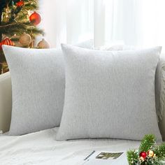 two white pillows sitting on top of a bed next to a christmas tree