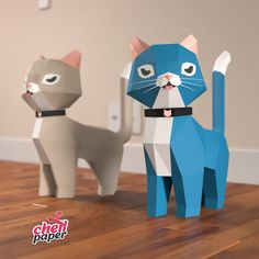 two paper cats standing next to each other on a wooden floor