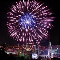 fireworks in the night sky over a city with tall buildings and spires on both sides