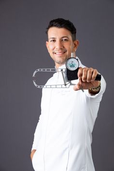 a man in white shirt holding a black and silver device with his arm around the clock