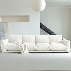 a white couch sitting in the middle of a living room next to a stair case