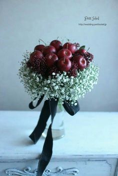 a bouquet of apples and baby's breath in a vase