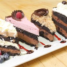 three different types of cake on a white plate with chocolate and raspberry toppings