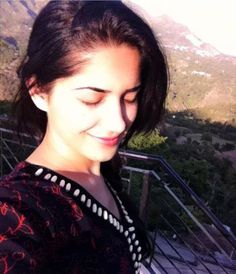 a woman looking at her cell phone while standing in front of a mountain view area