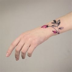 a woman's hand with a flower tattoo on the left side of her arm