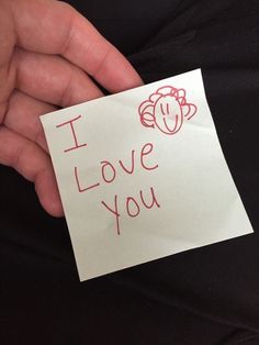 a person holding a piece of paper with the words i love you written on it