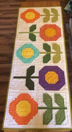 a quilted table runner with flowers and arrows on the front, along with an arrow in the middle