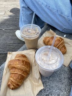 two croissants and a drink are sitting on the ground