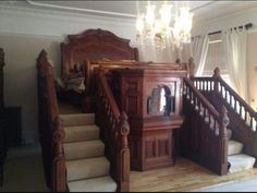 a bed sitting in the middle of a living room next to a stair case and chandelier