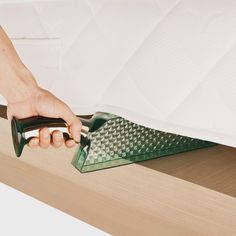 a person is using a vacuum to clean the bottom of a bed with a mattress pad