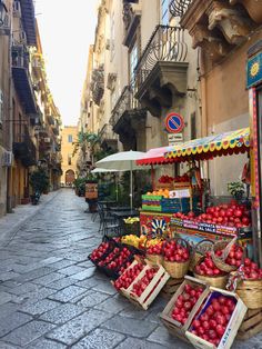 an open air market with fruit and vegetables on display in the middle of a street