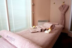 towels and candles are laid out on the bed in this spa room with pink walls