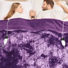 a man and woman laying in bed next to each other with ear buds on their ears