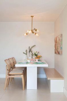 a dining room table with two chairs and a bench in front of it, next to a painting on the wall