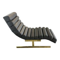 a black leather chaise lounge chair with gold legs and footrests on a white background