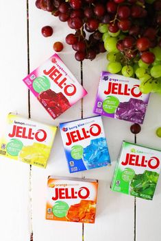 four jello candy bars sitting on top of a table next to grapes and grapes