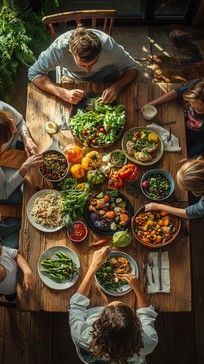 several people sitting around a table with plates of food and bowls of salads on it