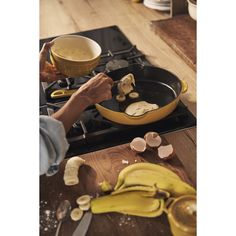 a person cooking food on top of a stove with bananas and other ingredients around it