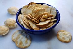 a blue bowl filled with crackers on top of a white counter next to cookies