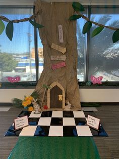 a room with a tree, checkerboard floor and bulletin board on the wall