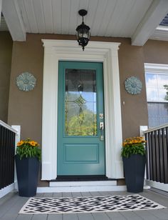 a blue front door with two planters on the porch