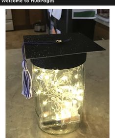 a graduation cap on top of a mason jar filled with string lights and a tassel