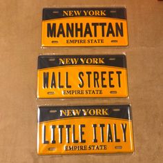 three new york license plates with the words manhattan and wall street written in black on them