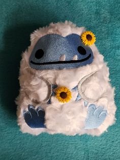 a stuffed animal with sunflowers on it's head sitting on a blue carpet