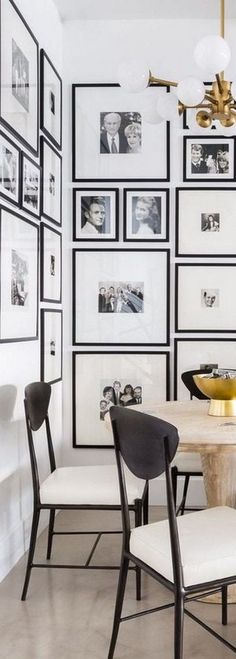 a white dining room with black and white pictures on the wall, chandelier and chairs